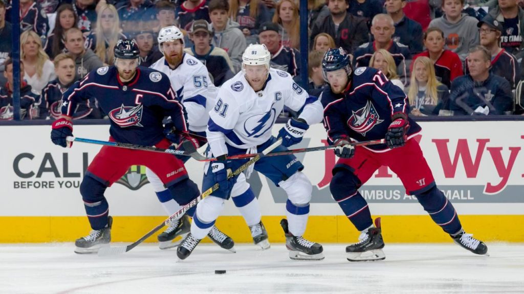 Two Jackets players seek the puck against a tampa player